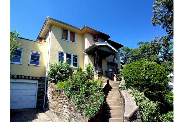 View of front facade with stucco siding, stairway, an attached garage, and stone siding