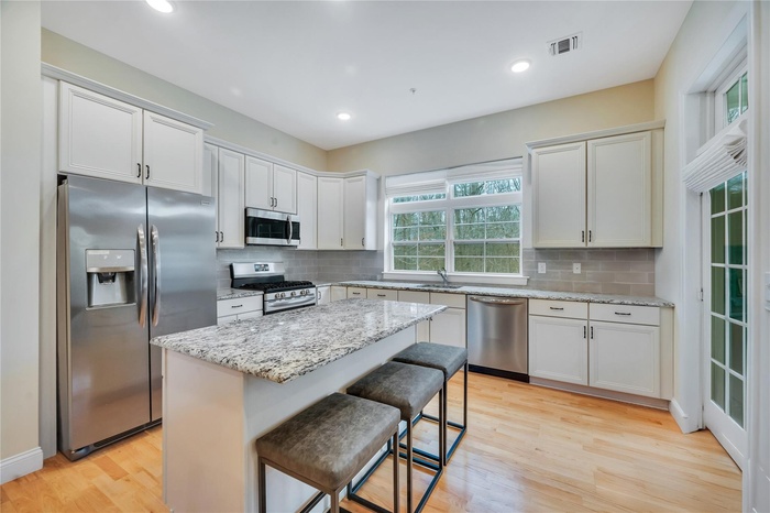 Kitchen with light wood finished floors, visible vents, a sink, and appliances with stainless steel finishes