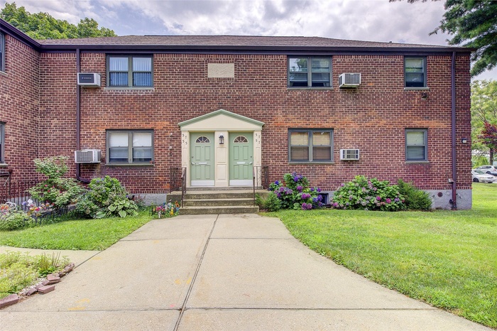 View of front of home with brick siding, a front yard, and entry steps