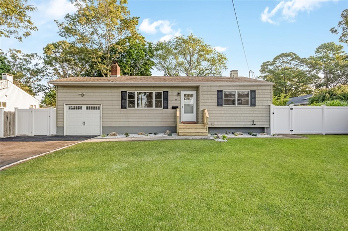 Single story home featuring a gate, a chimney, driveway, and an attached garage