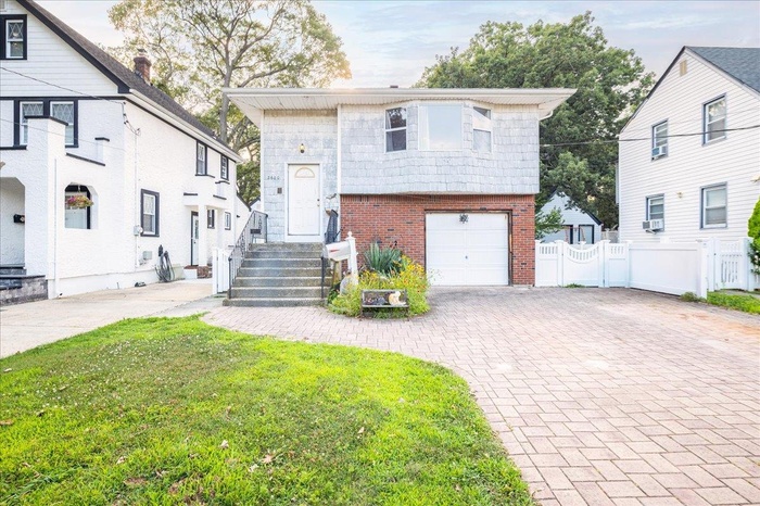 View of front of house featuring brick siding, decorative driveway, and a garage