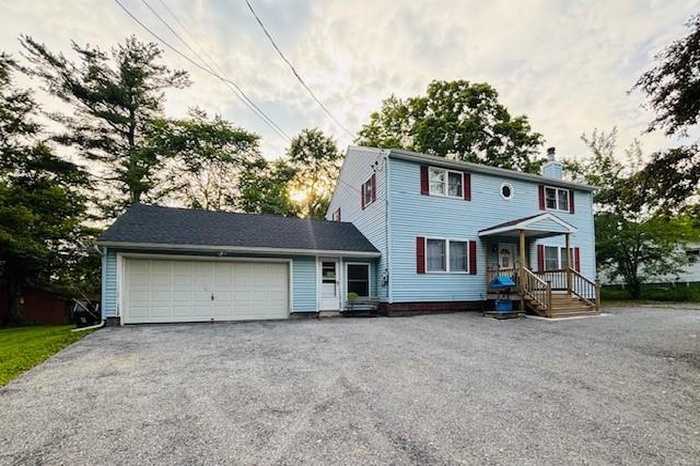 View of front facade featuring a garage, a chimney, and asphalt driveway