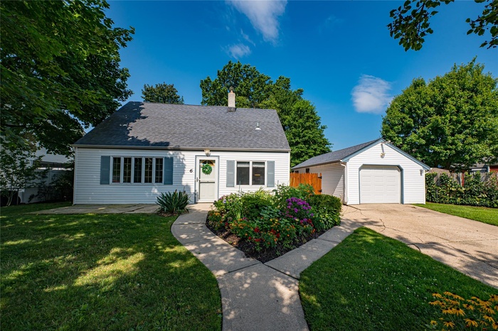 View of front of home featuring an outbuilding, a chimney, concrete driveway, a garage, and roof with shingles