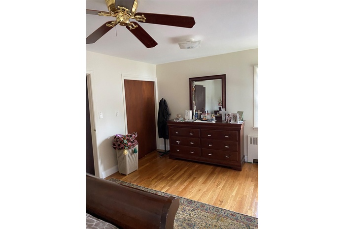 Bedroom featuring radiator, light wood-style flooring, a closet, and ceiling fan