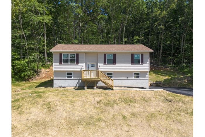 Raised ranch with a front lawn and a forest view