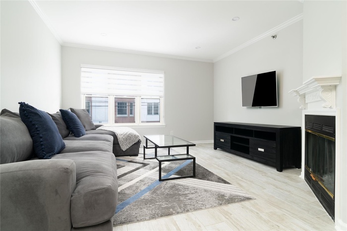 Living area with ornamental molding and light wood-style floors