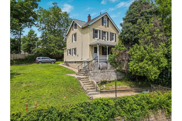 View of front of house with a porch, a chimney, and stairway