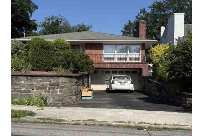 View of front of property with an attached garage, driveway, and a chimney