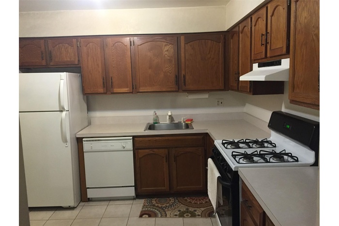 Kitchen with white appliances, under cabinet range hood, light countertops, and light tile patterned floors