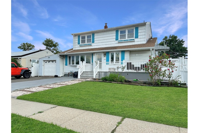 View of front of house with covered porch, a shingled roof, asphalt driveway, and a chimney
