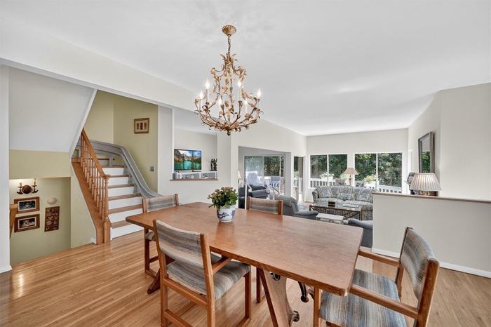 Dining room with a chandelier, light wood-style floors, and stairs