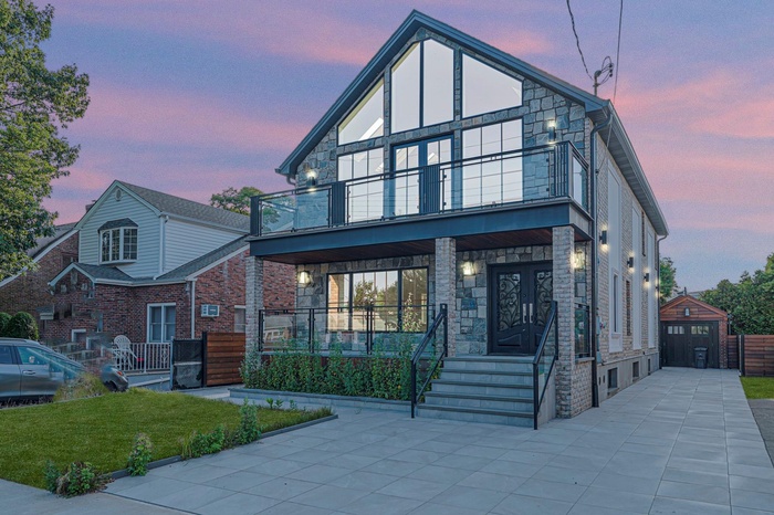 Modern home with stone siding, a balcony, and covered porch