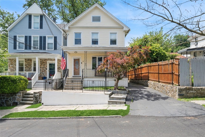 View of front of house featuring a porch, a fenced front yard, and asphalt driveway