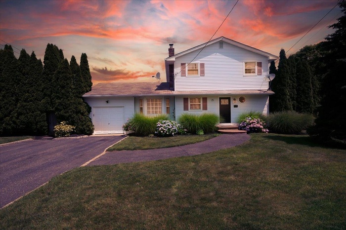 Colonial-style home featuring an attached garage, a chimney, asphalt driveway, and a yard