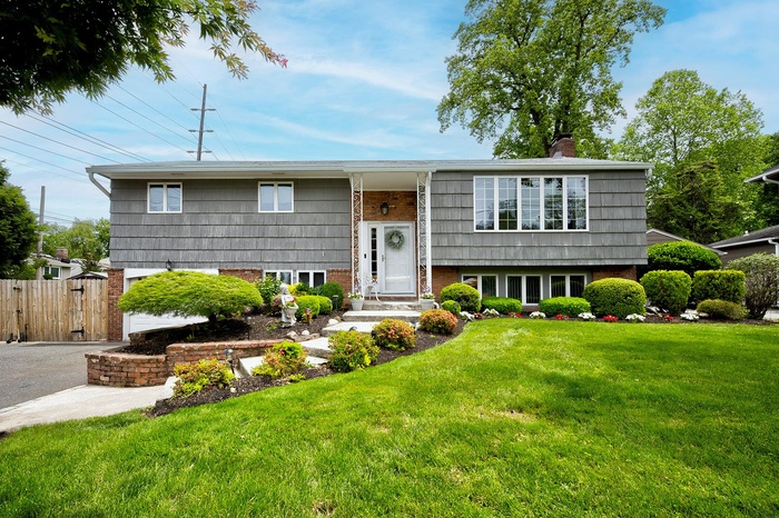 Raised ranch with a chimney, asphalt driveway, and a gate