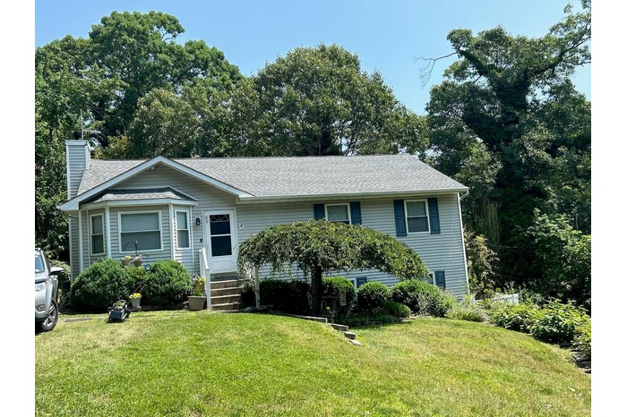 View of front facade featuring a chimney, roof with shingles, and a front lawn
