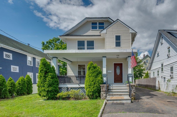 View of front facade featuring covered porch and asphalt driveway
