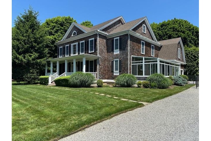 View of front of property featuring covered porch, a shingled roof, and a front lawn