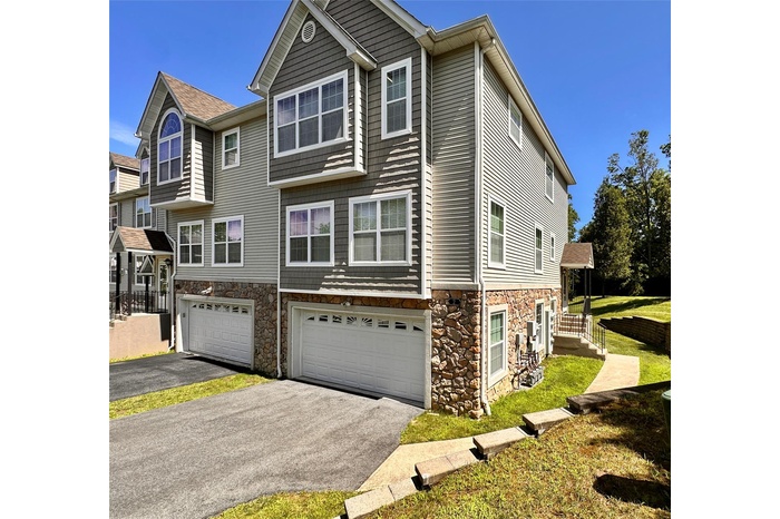 View of front of house featuring stone siding, a 2-car garage, and an asphalt driveway