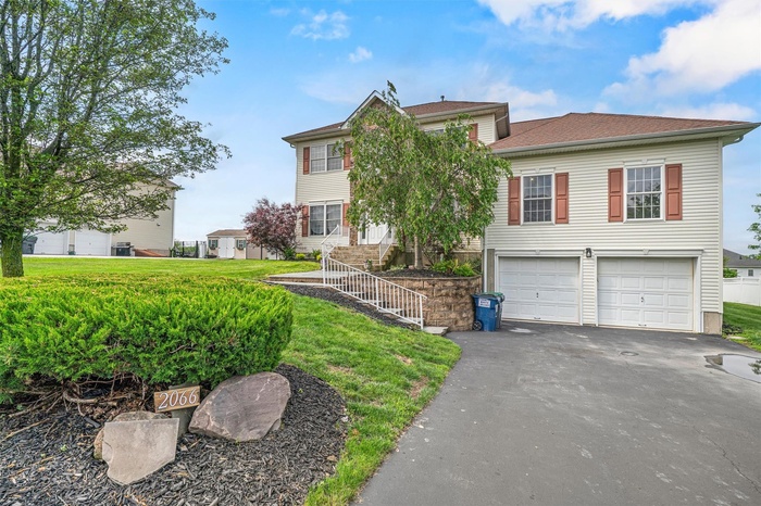 View of front of home featuring asphalt driveway, an attached garage, and front yard
