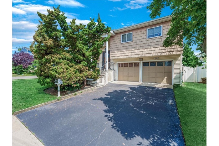 View of front of property with driveway, a garage, and a gate