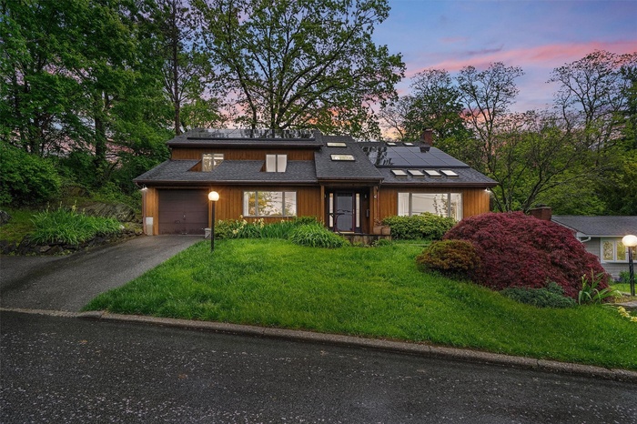 Contemporary home with solar panels, asphalt driveway, an attached garage, and a yard