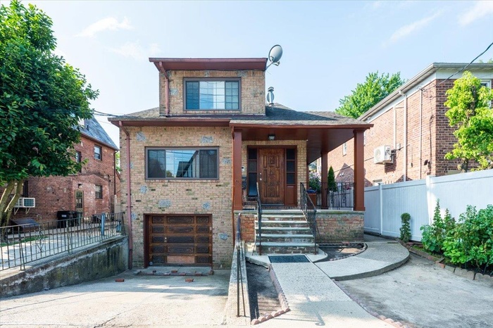 View of front facade featuring a garage, driveway, brick siding, and a porch