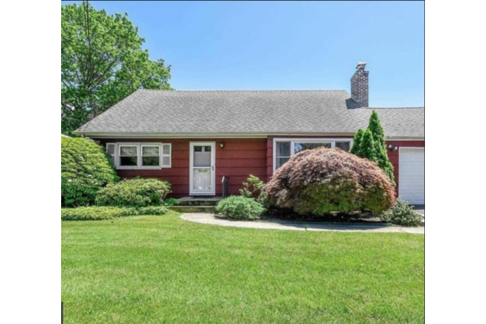 Single story home featuring a chimney, a front lawn, and a garage