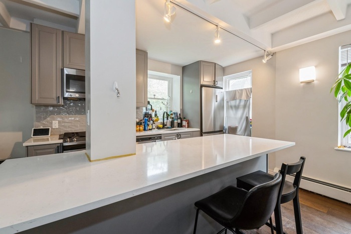 Kitchen featuring appliances with stainless steel finishes, gray cabinetry, rail lighting, a sink, and backsplash