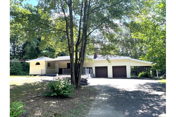 Ranch-style house featuring driveway, a porch, a carport, a garage, and a chimney