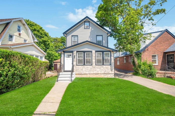 View of front of house with a front yard and stone siding