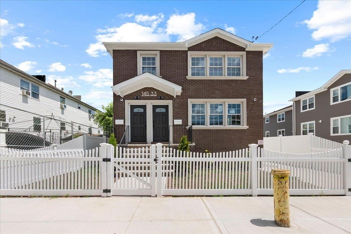 Traditional-style home with brick siding, a gate, and a fenced front yard