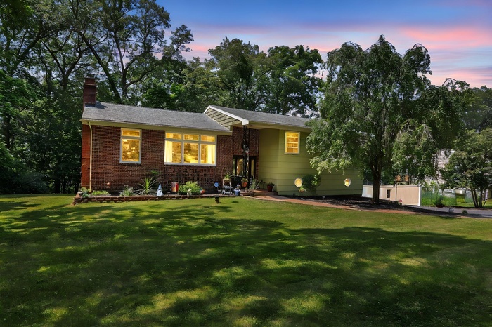 View of front of home featuring a front lawn, a chimney, and brick siding