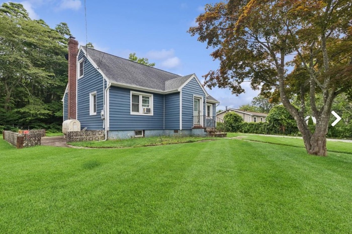 View of home's exterior with a chimney, a lawn, roof with shingles, and heating fuel