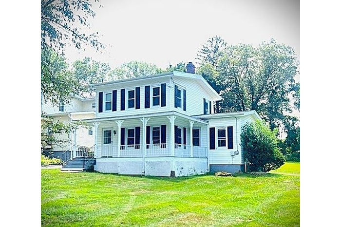 View of front facade with a porch, a chimney, and a front yard