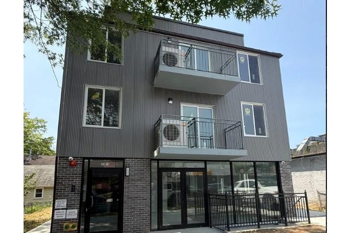 View of front of property featuring a balcony, brick siding, and french doors