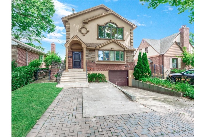 View of front facade featuring decorative driveway, stucco siding, an attached garage, and brick siding