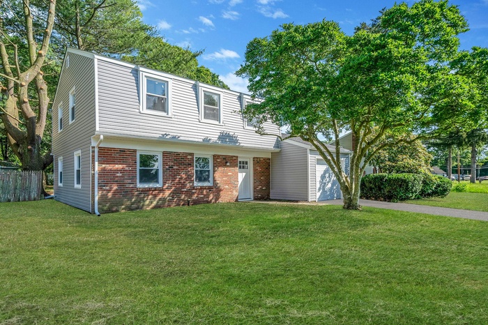 Colonial-style house featuring brick siding, a garage, and asphalt driveway