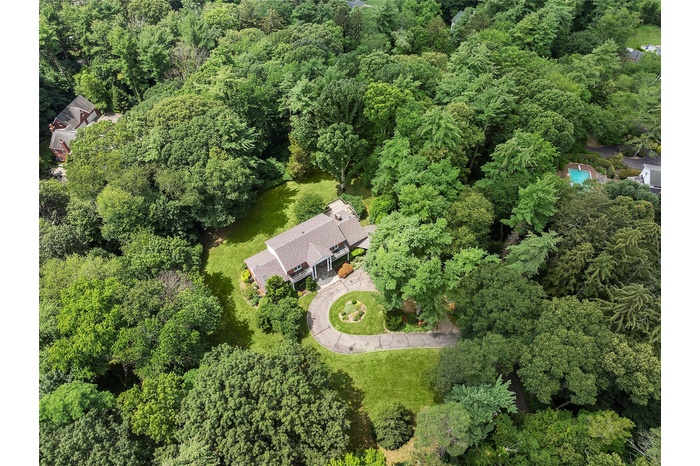 Aerial view of property and surrounding area with a heavily wooded area