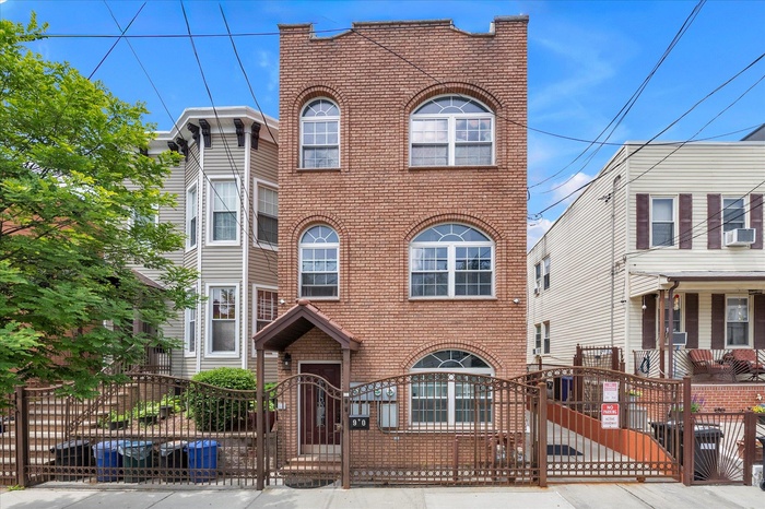 View of front of property featuring brick siding, a gate, a fenced front yard, and cooling unit