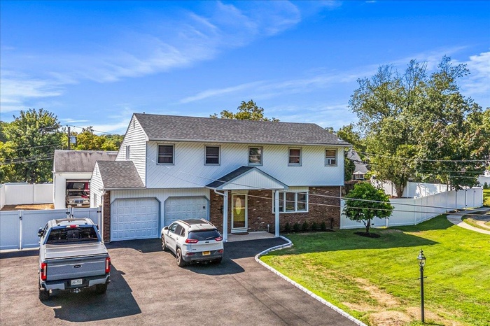 Traditional home featuring brick siding, driveway, a shingled roof, and an attached garage