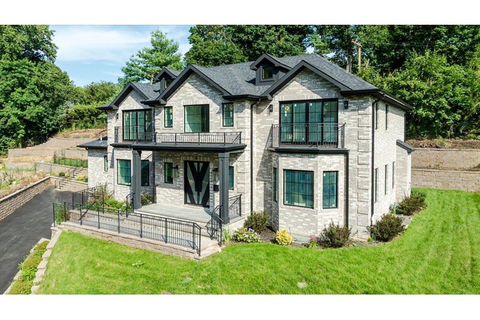 French country home with a balcony, brick siding, a front yard, driveway, and a porch