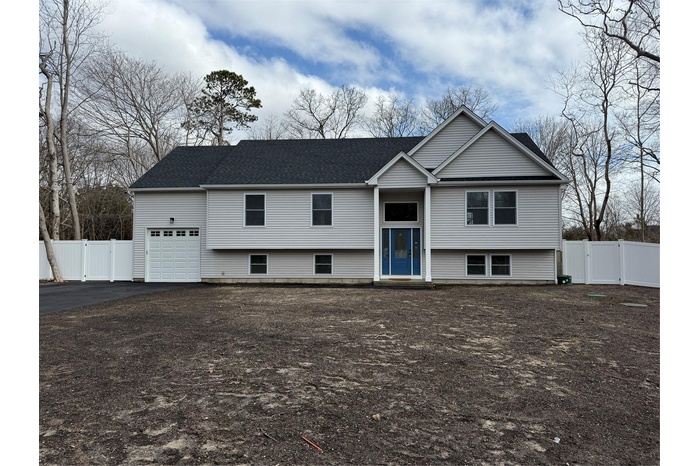Split foyer home featuring a gate, a garage, driveway, and roof with shingles