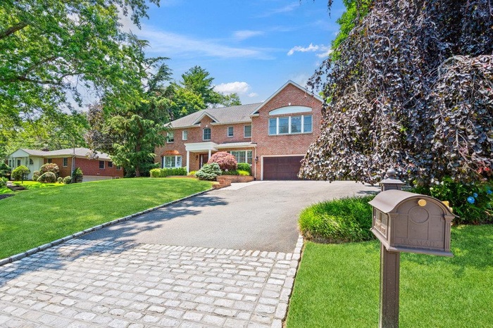 View of front of home featuring driveway, brick siding, an attached garage, and a front yard