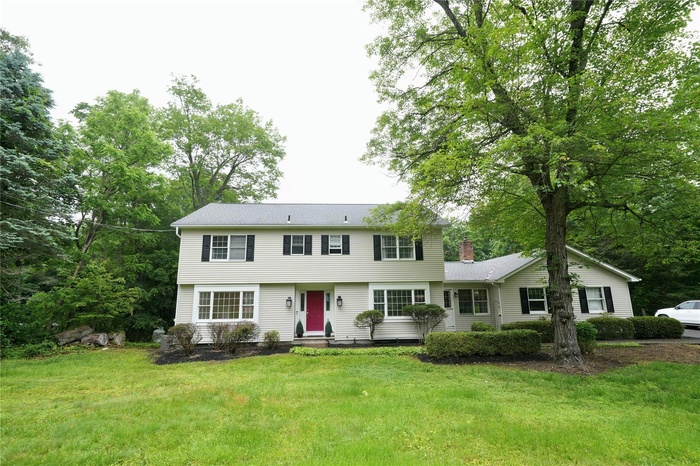 Colonial inspired home with a front lawn, a chimney, and entry steps