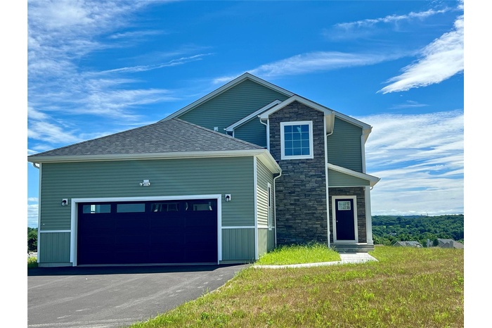 View of front of house featuring driveway, a garage, and stone siding