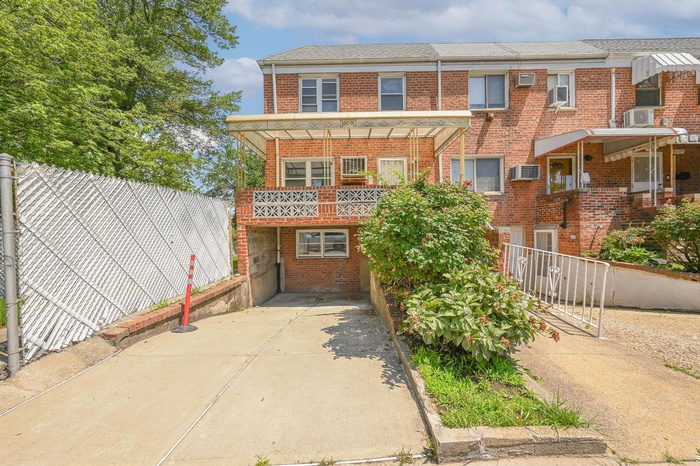 Townhome / multi-family property with brick siding, a balcony, and concrete driveway