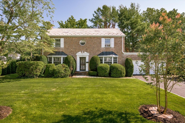View of front facade featuring a front lawn, brick siding, and a garage
