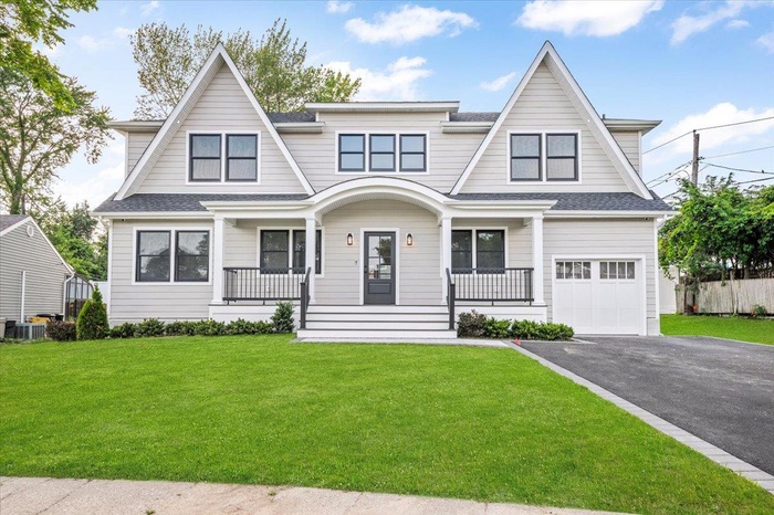 Shingle-style home featuring covered porch, driveway, a garage, and roof with shingles
