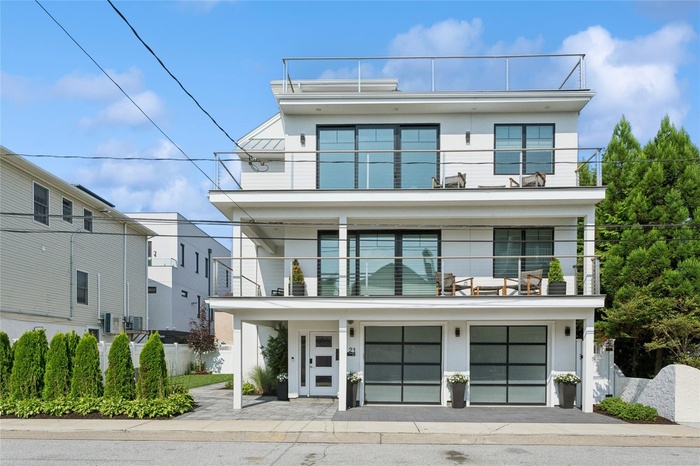 View of front facade featuring a balcony, stucco siding, a garage, and driveway